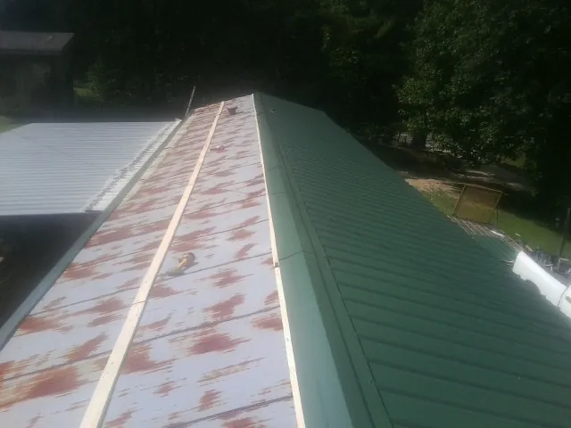 Old rusted panels beside newly installed green metal roofing — Wind Damage Roof Repair by Roofing Brothers in Plantersville