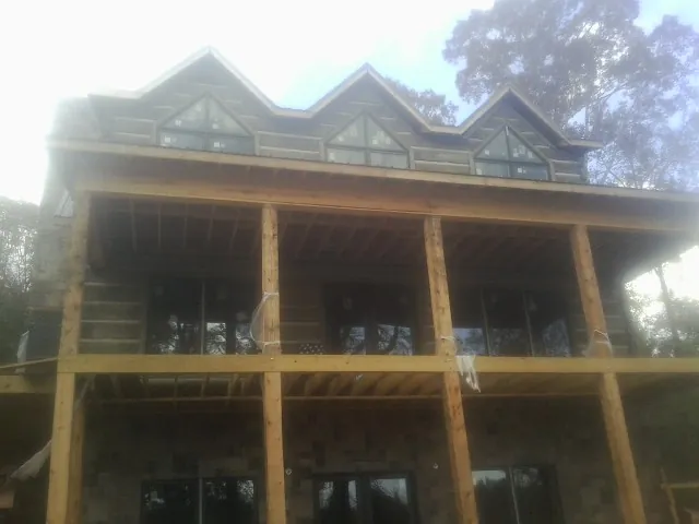 Dormers and porch framing on a large log home under construction — Roof Coating work by our crew in Plantersville